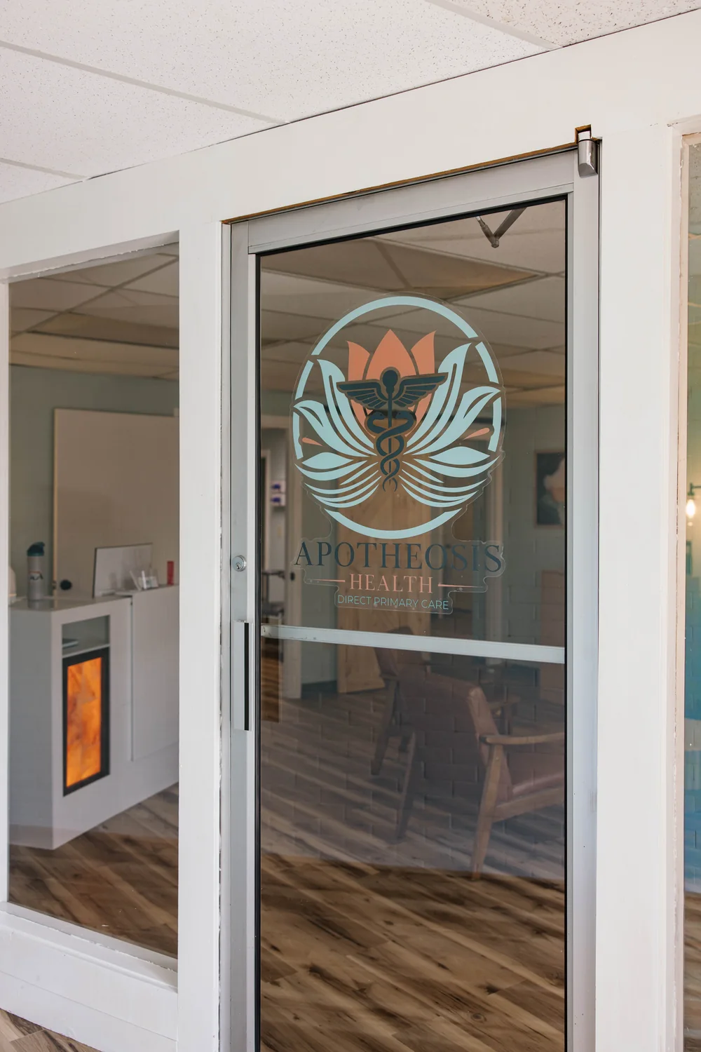 The glass entrance to Apotheosis Health displaying the practice logo